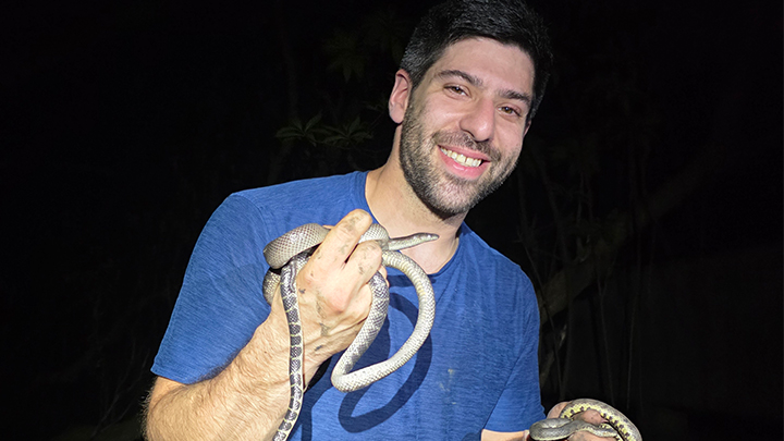 Man holding a snake in each hand