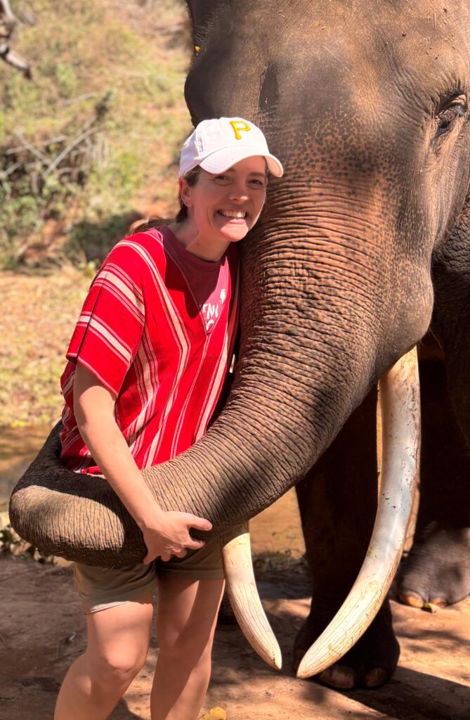 Woman standing next to elephant.