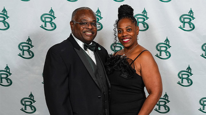 Man and woman in formal attire posting in front of a SRU backdrop.